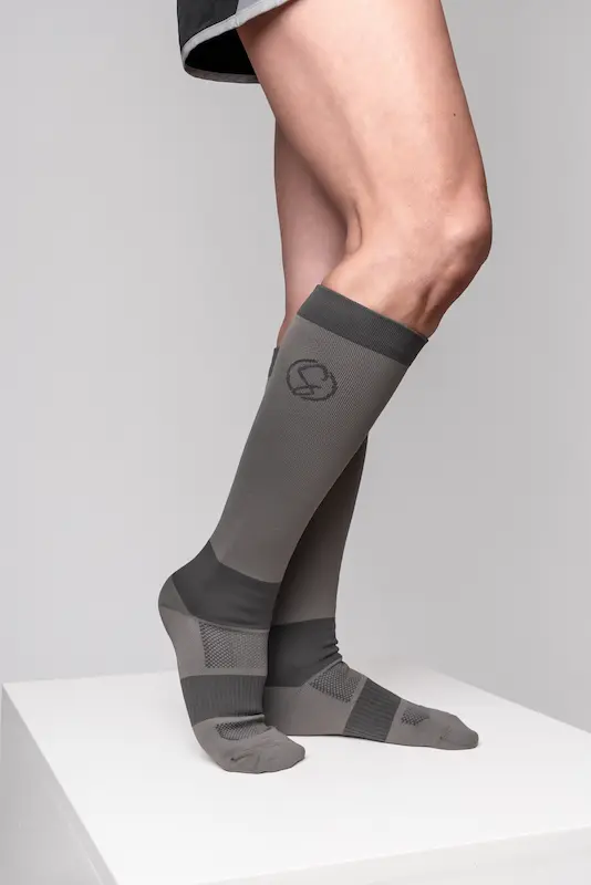 Stridely charcoal grey compression socks photographed on studio pedestal