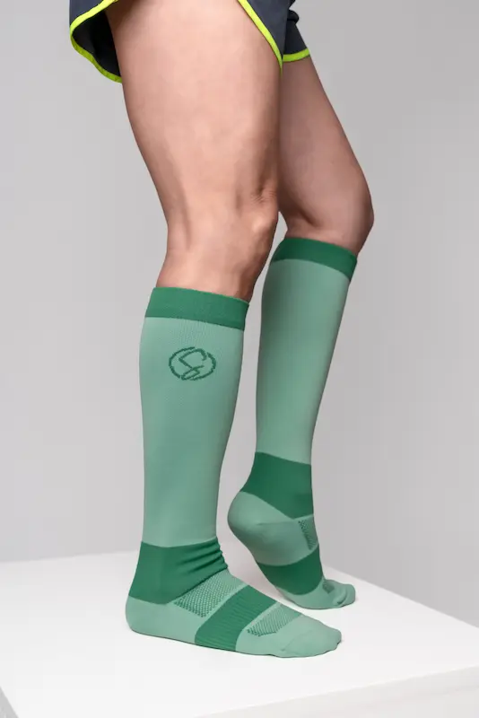 Stridely sage green compression socks photographed on white studio pedestal