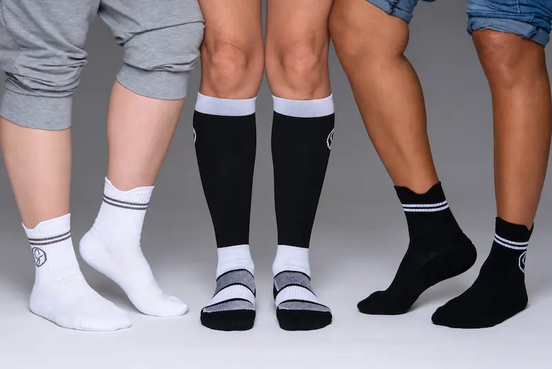 Three models wearing Stridely white crew, black knee-high, and black crew compression socks